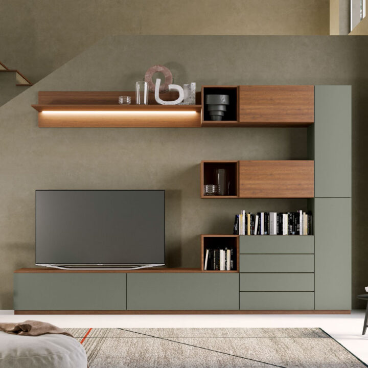 Soluzione d'arredo composta da mobili componibili per il soggiorno di colore verde salvia, con dettagli in legno caldo, composta da mobile tv, elementi libreria, mensole, cassettiera e pensili con sportelli. Finiture in laminato legno e colore pieno RAL. Soggiorno modulare Quattrolati di Benigni Mobili.